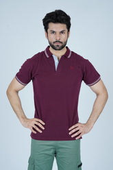 Man wearing a maroon polo shirt with a brand logo on a light gray background